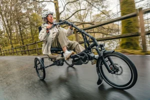 Older lady riding the HASE Kettwiesel ONE on a bike path