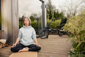old lady practising yoga with the HASE kettwiesel standing in the background